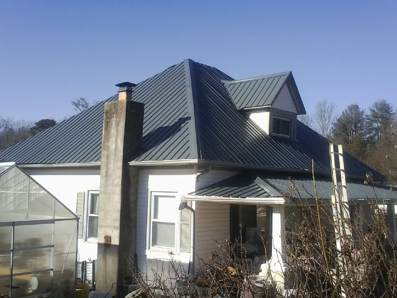 Dark blue standing seam metal roof on a white farmhouse with dormer — Slate & Tile Roof Repair by Roofing Brothers in Osage Beach