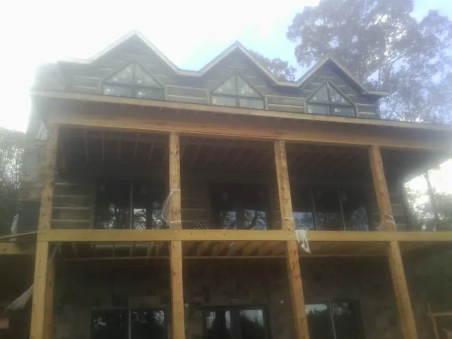 Dormers and porch framing on a large log home under construction — Roof Coating work by our crew in Osage Beach