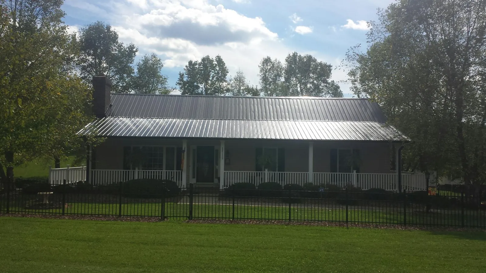 Gray metal roof on a brick ranch with a full width front porch — Gutter Guard Installation work by our crew in Osage Beach