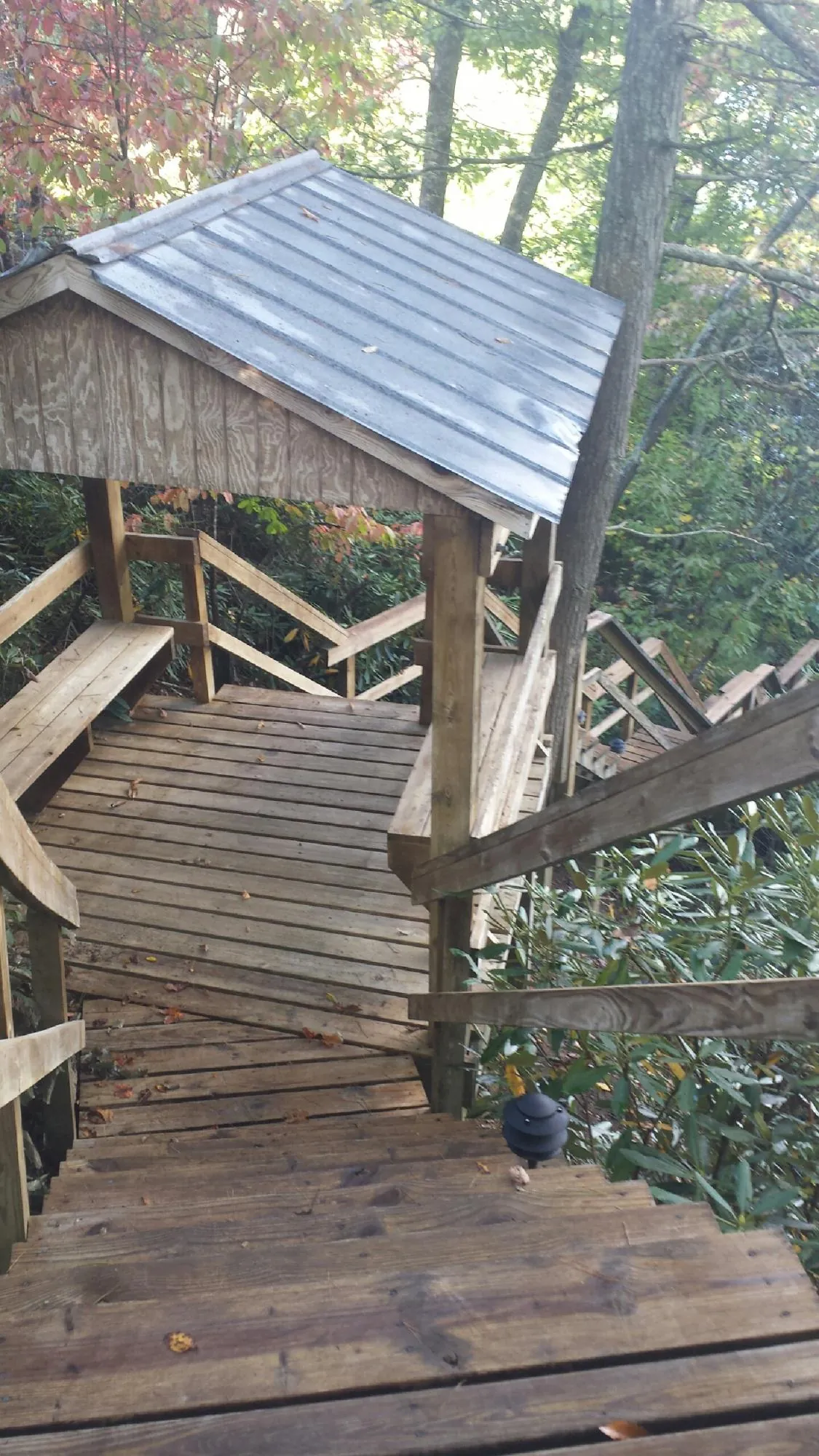Metal roofed shelter over wooden steps on a wooded walkway — Skylight Repair & Installation work by our crew in Osage Beach