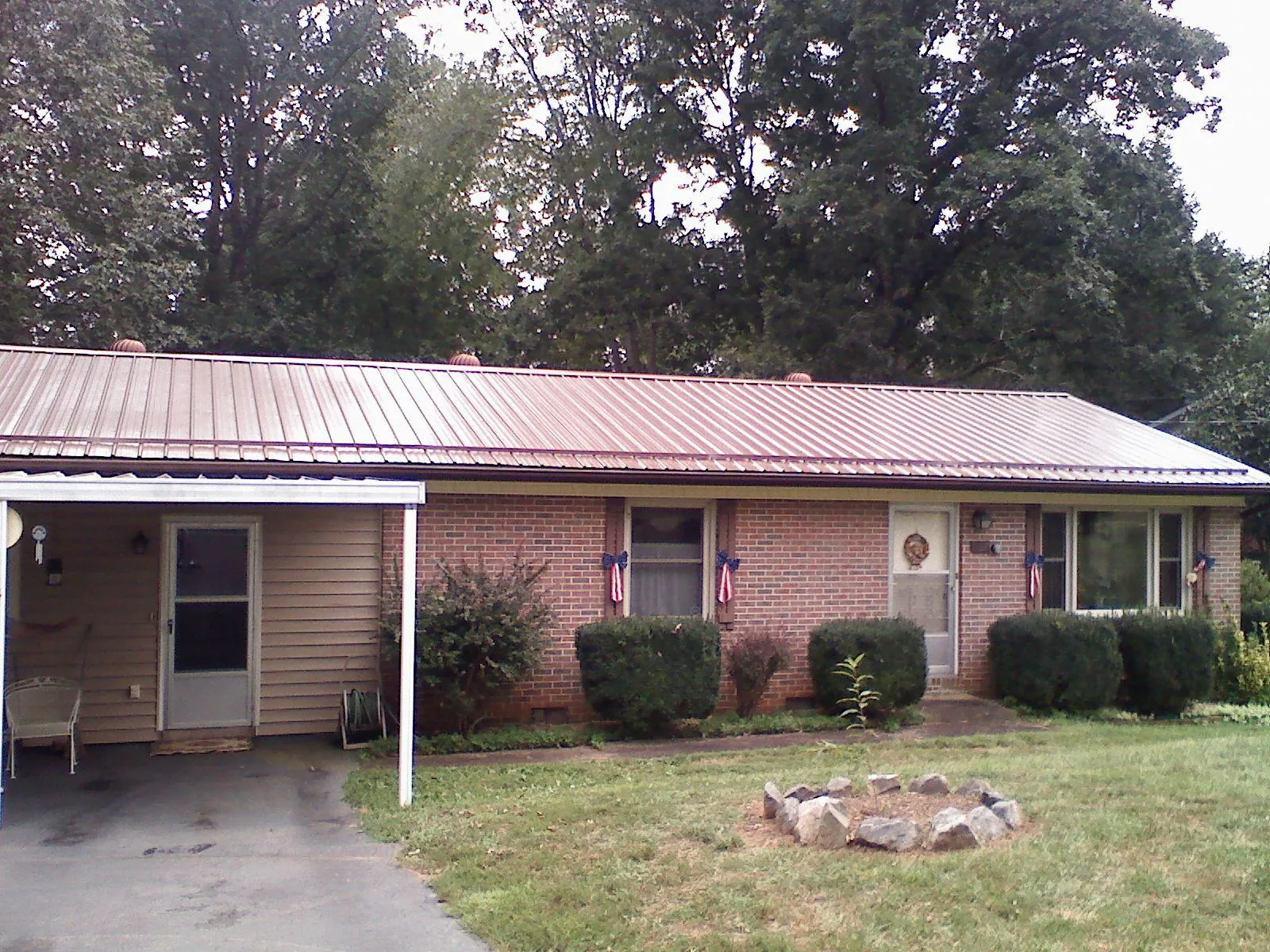 Bronze metal roof and carport on a brick ranch home — Roof Repair work by our crew in Osage Beach
