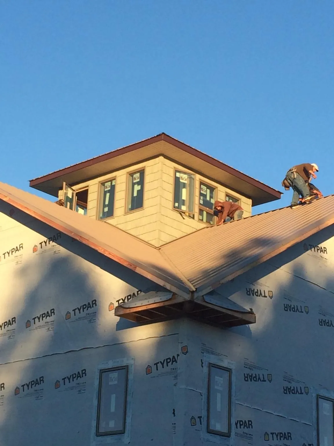 Roofers working around a rooftop cupola on a new metal roof at sunset — Roof Waterproofing in Osage Beach by Roofing Brothers